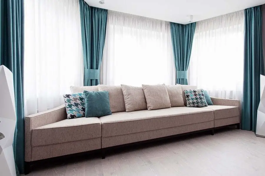 large-modern-couch-in-the-room-near-a-big-window-light-and-turquoise-tones